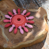 Red piece from the Nic stacking tower wooden toy used in the middle of a mandala with Grapat mandala pieces.