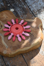 Red piece from the Nic stacking tower wooden toy used in the middle of a mandala with Grapat mandala pieces.