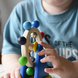 Close-up of a young child's handsswpinning the Nic Toys ferris wheel colorful wooden toy.