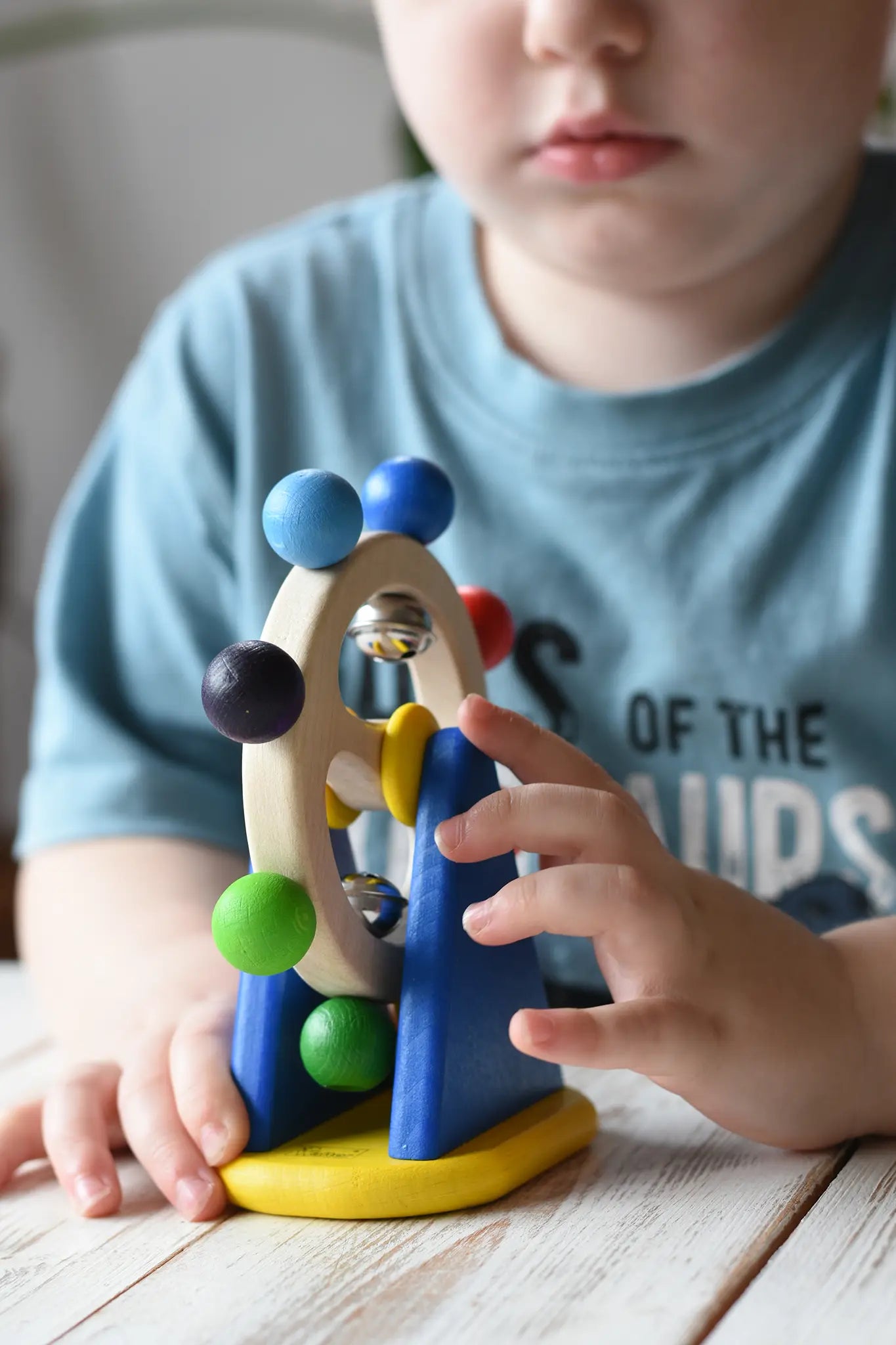Close-up of a young child's handsswpinning the Nic Toys ferris wheel colorful wooden toy.