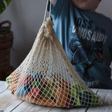 Child lifting a net bag filled with Glückskäfer Wooden Bio Geometric Building Blocks in a 58 Piece Set.