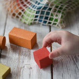 Close up of a child's hand playing with blocks from the Gluckskafer Wooden Bio Geometric Building Blocks 58 Piece Set. 