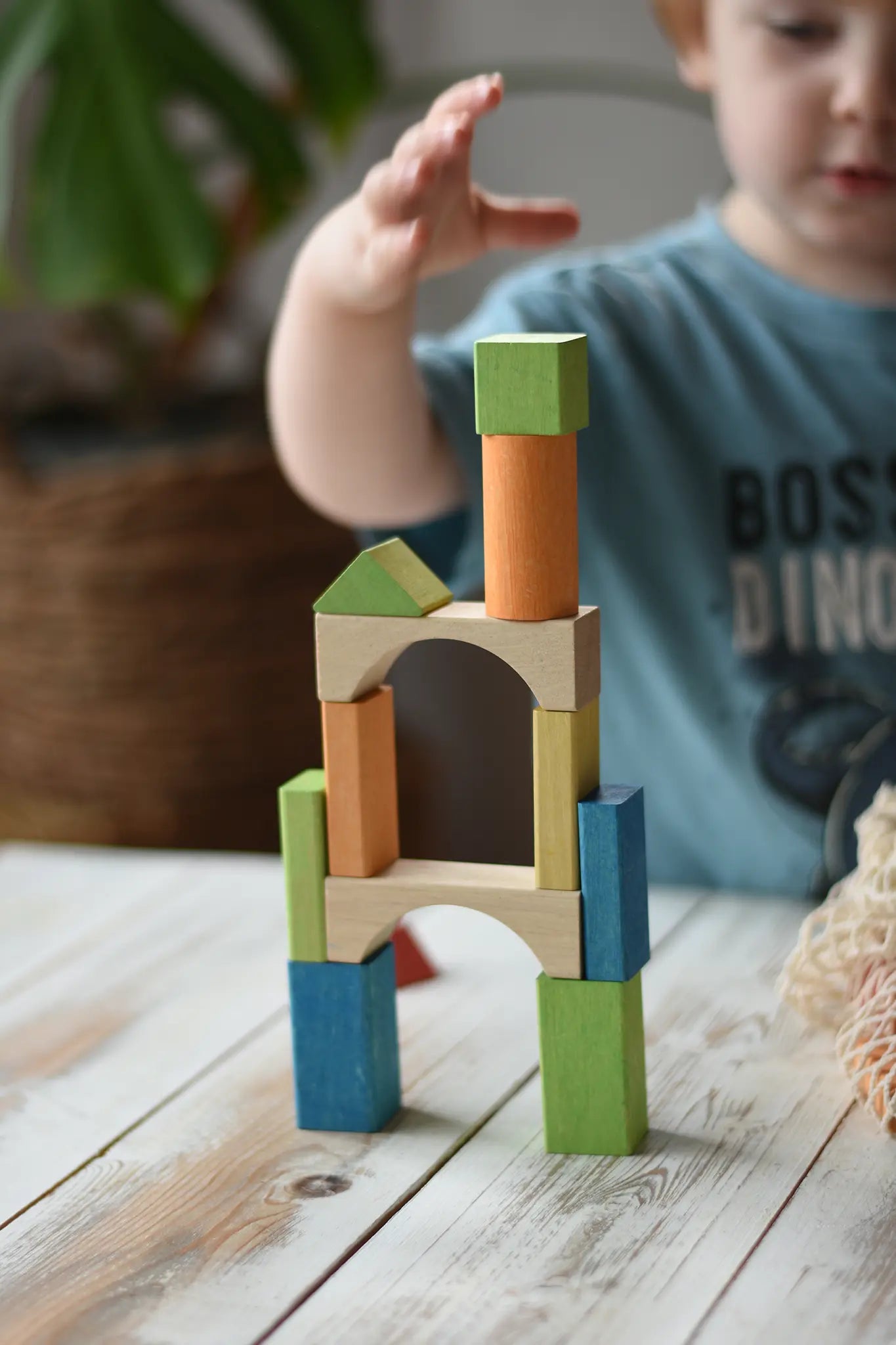 Child stacking the blocks from the Glückskäfer Wooden Bio Geometric Building Blocks, 58 Piece Set.