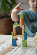 Child stacking the blocks from the Glückskäfer Wooden Bio Geometric Building Blocks, 58 Piece Set.
