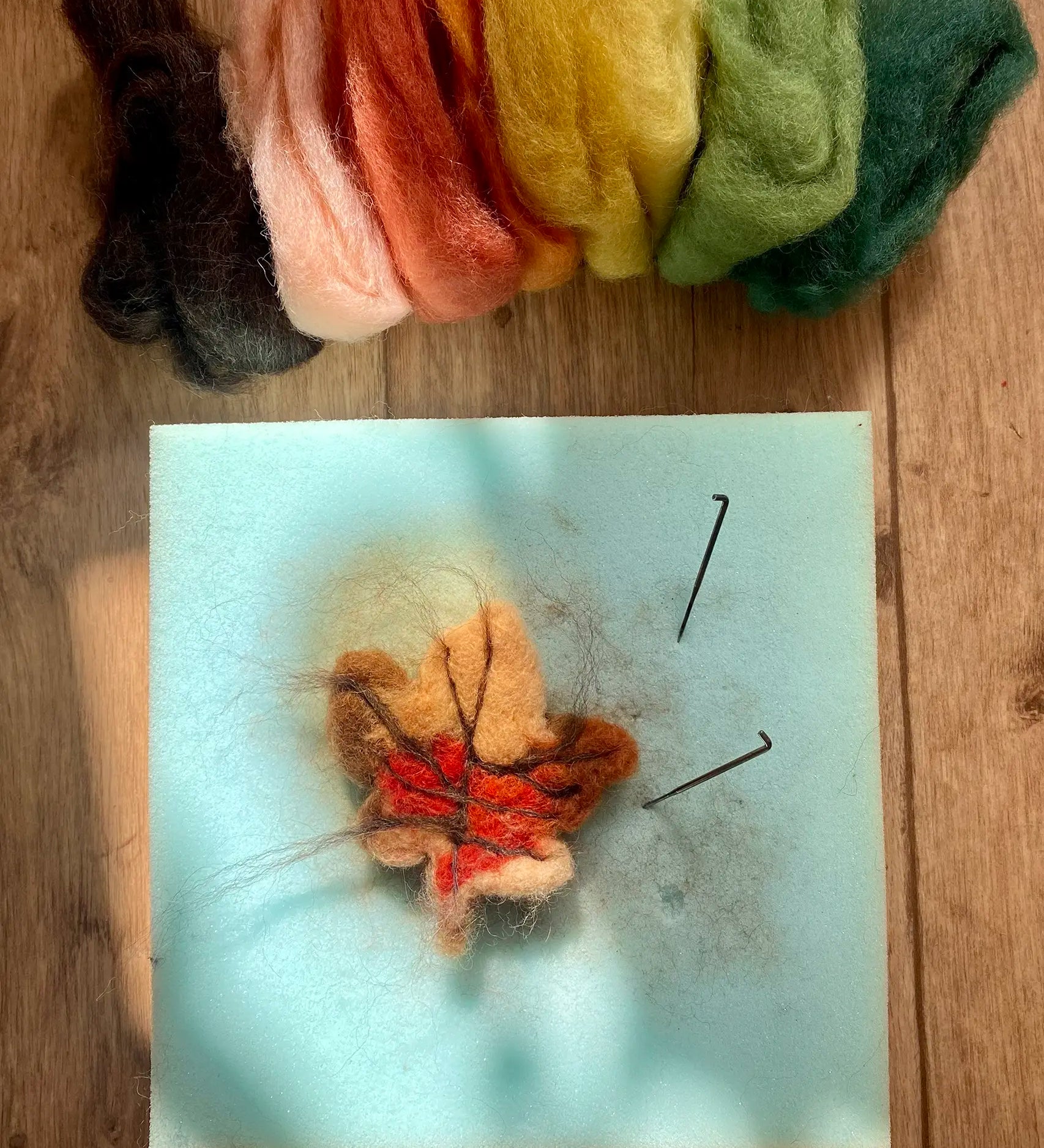 A small handcrafted Gluckskafer felted wool autumn leaf with Nic Toys felting needles.