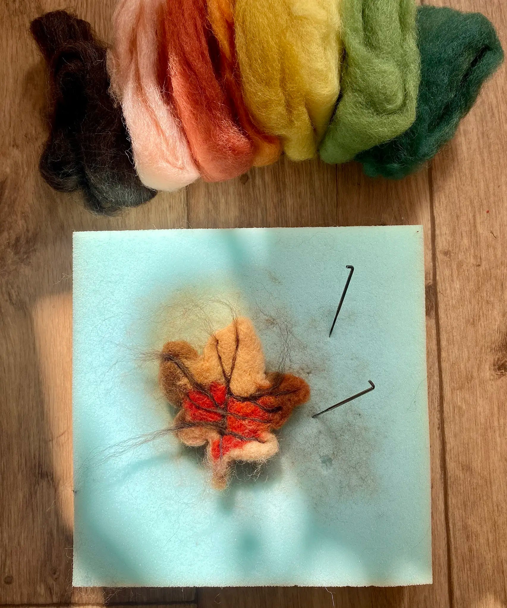 A small handcrafted Gluckskafer felted wool autumn leaf with Nic Toys felting needles.