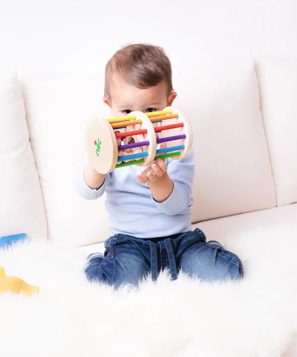Nic Toys Rattle n Roll - a child playing with a colourful wooden baby toy made with rainbow stained rungs and natural wooden marbles.