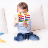 Nic Toys Rattle n Roll - a child playing with a colourful wooden baby toy made with rainbow stained rungs and natural wooden marbles.