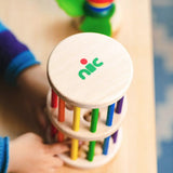 Nic Toys Rattle n Roll - a child playing with the wooden rolling wheel musical toy, which has rainbow stained rungs and wooden marbles.
