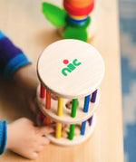 Nic Toys Rattle n Roll - a child playing with the wooden rolling wheel musical toy, which has rainbow stained rungs and wooden marbles.
