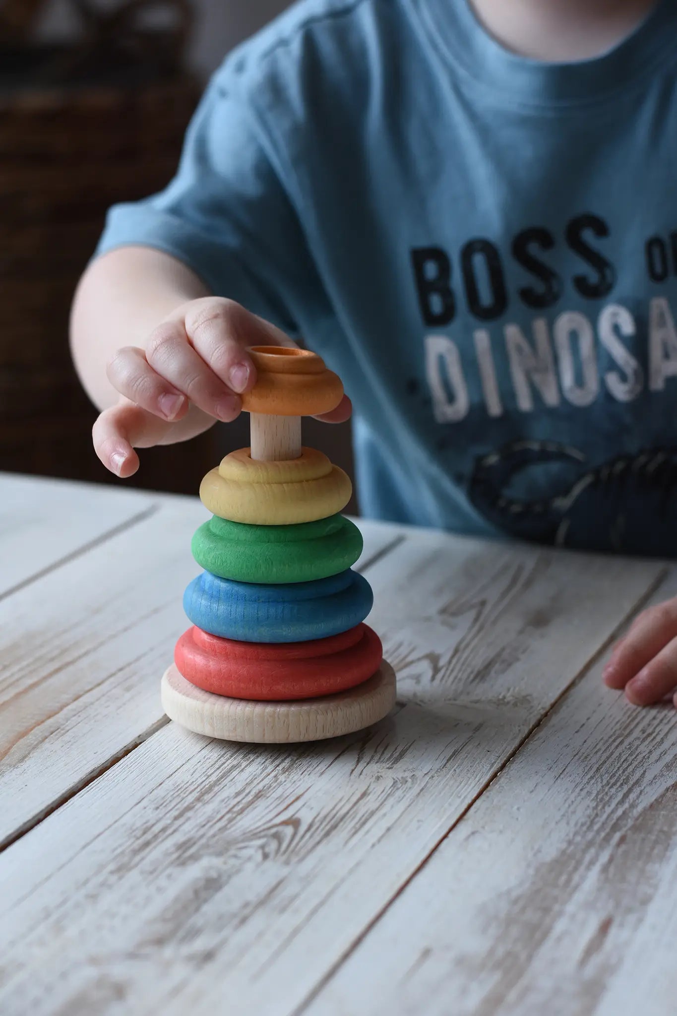 Child stacking colorful wooden rings on the Nic wooden Classic Stacking Tower baby toy natural wood base.