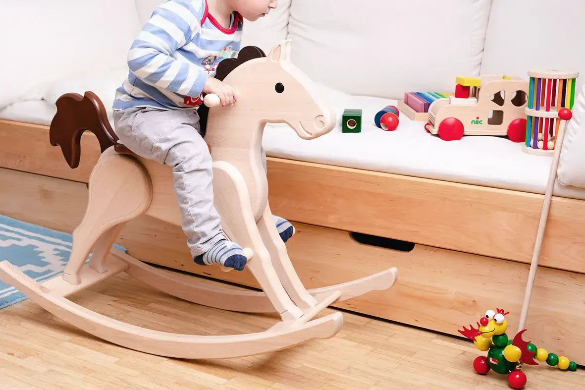 Nic Toys rocking horse, heirloom quality made from wood with a natural finish and brown mane and tail in playroom setting.