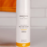Green People Self Tan Lotion 150ml with an orange towel in the background