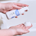 A person has pumped some of the foaming face wash to show the texture of the product in their hand