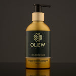 Olew naturally cleansing Conditioner, vegan haircare which is SLS and Paraben Free. In a gold and dark green bottle with a push down pump on top. The image is on a dark grey background