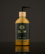 Olew Naturally Nourishing Curl Defining Cream, vegan haircare which is SLS and Paraben Free in a gold and dark green bottle with an push down pump top, on a dark grey background