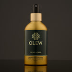 Olew Hold Spray - Curl Keeper, giving natural hold and shine. Vegan haircare which is SLS and Paraben Free, in a gold and dark green bottle with a spray mist pump on top. The image is on a dark grey background