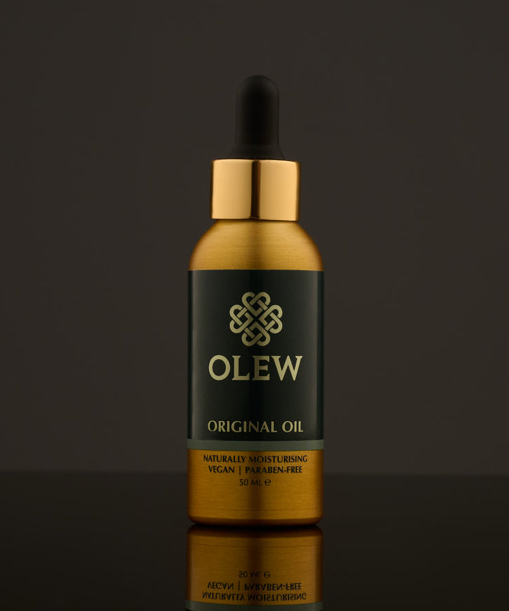 Olew Original Hair Oil, naturally moisturising vegan haircare which is SLS and Paraben Free, in a gold and dark green bottle with a pipette on top. The image is on a dark grey background