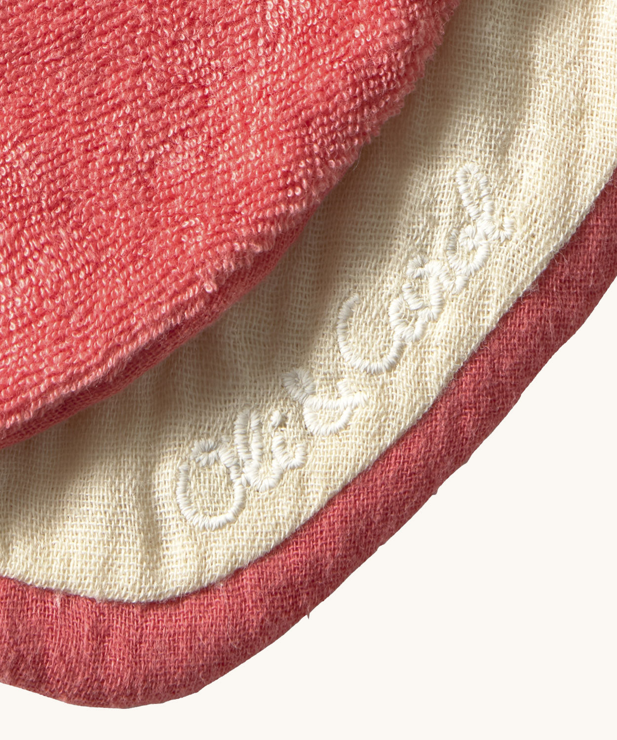 A close up of the  Oli & Carol Peppa the apple baby bib available at Babipur showing the brand name stitch detail on the inside of the bib