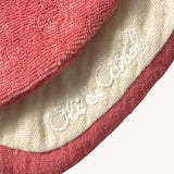 A close up of the  Oli & Carol Peppa the apple baby bib available at Babipur showing the brand name stitch detail on the inside of the bib