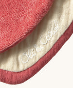 A close up of the  Oli & Carol Peppa the apple baby bib available at Babipur showing the brand name stitch detail on the inside of the bib