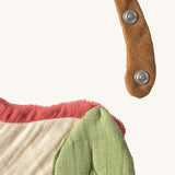 A close up of the  Oli & Carol Peppa the apple baby bib available at Babipur showing the popper fastener for size adjustment. 