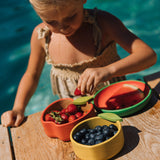 A child eating strawberries from the Oli & Carol Peppa the apple wooden bowl next to a lemon bowl available at Babipur. 