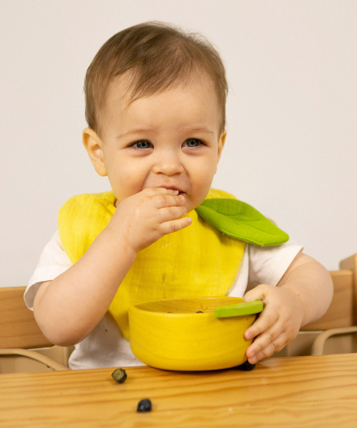 A child eating fruit from the Oli & Carol Lou the lemon wooden bowl set available at Babipur. 