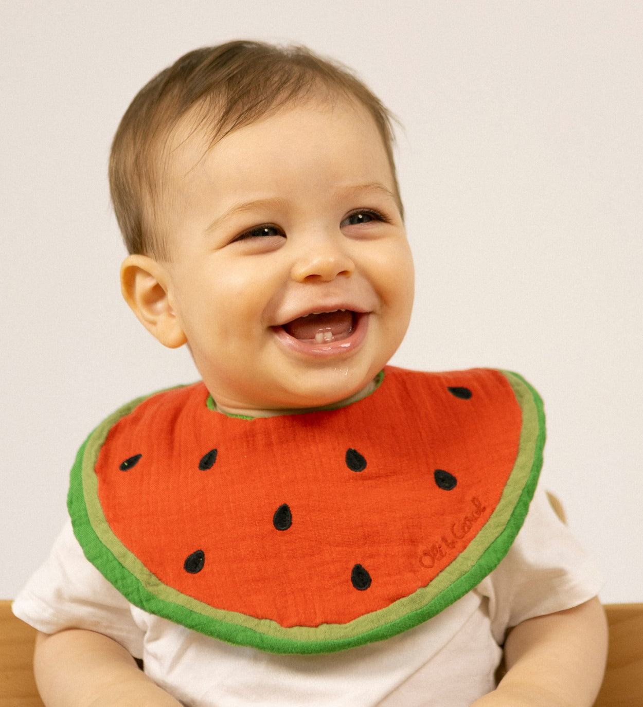 A baby wearing the Oli & Carol Wally the watermelon organic cotton baby bib available at Babipur 