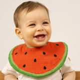 A baby wearing the Oli & Carol Wally the watermelon organic cotton baby bib available at Babipur 