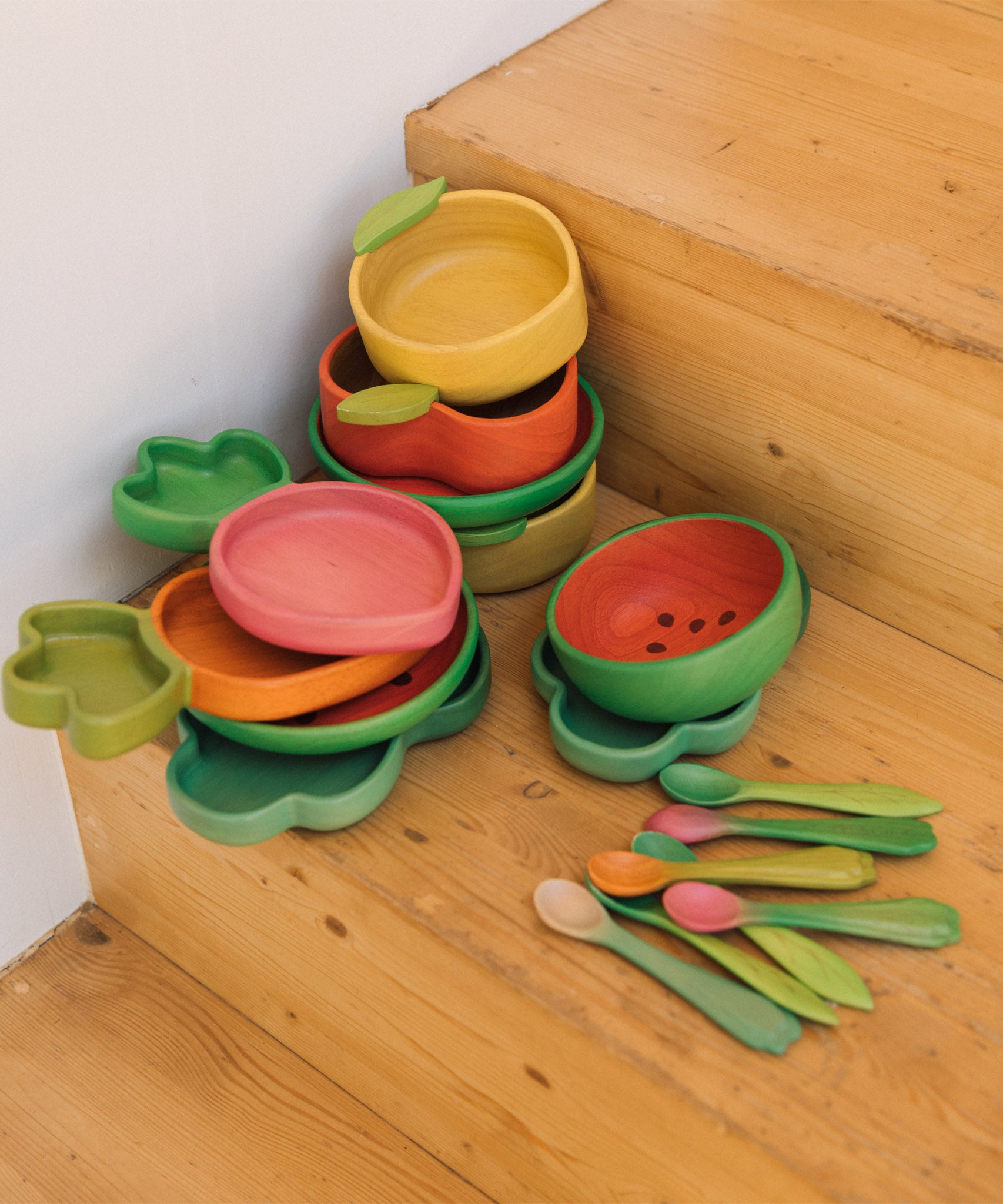 A stack of Oli Carol wooden bowls and plates on stairs. All bowls and plates are available at Babipur.