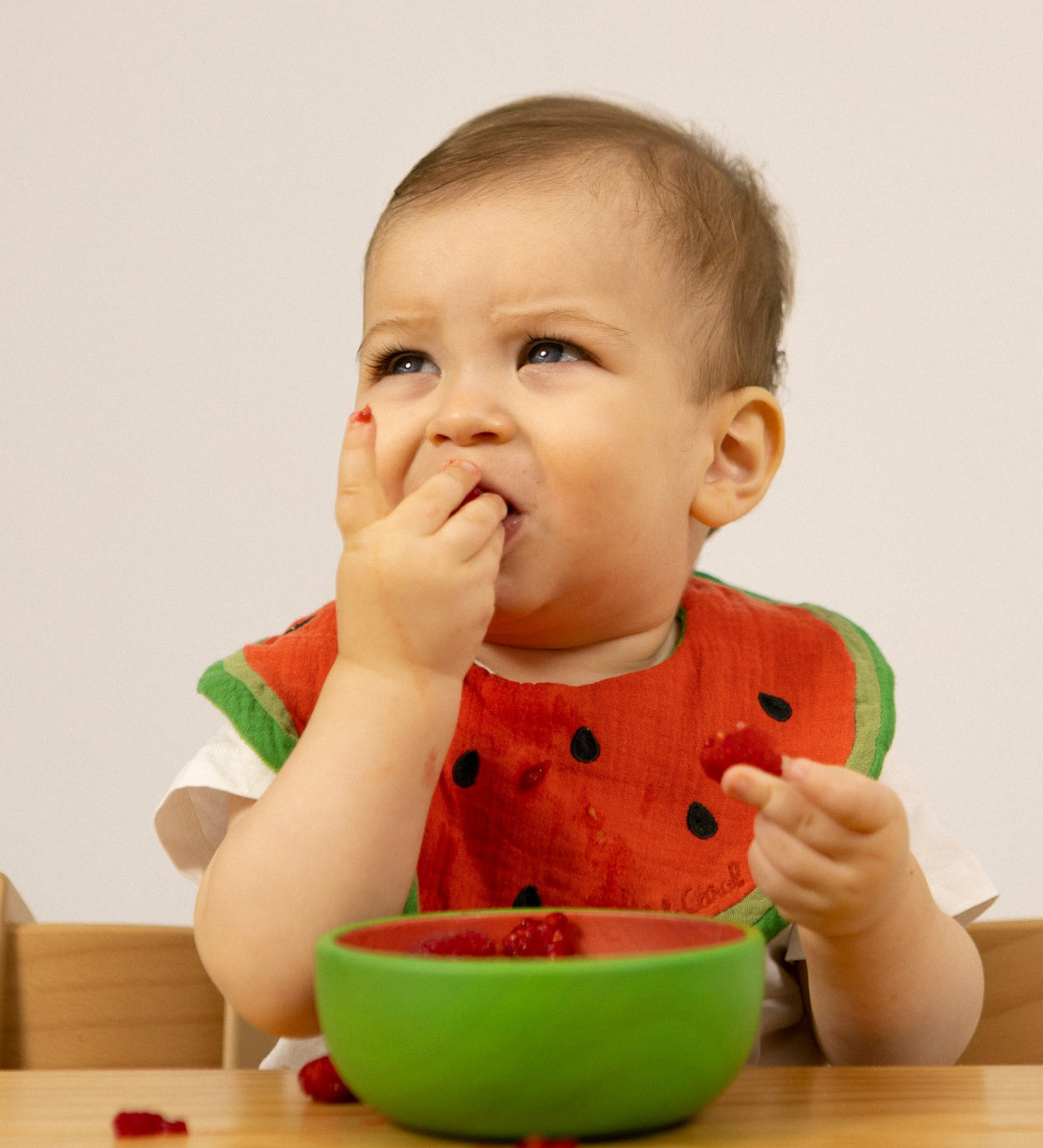 A baby eating fruit from the Oli & Carol Wally the watermelon wooden bowl available at Babipur. 