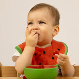 A baby eating fruit from the Oli & Carol Wally the watermelon wooden bowl available at Babipur. 
