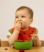 A baby eating fruit from the Oli & Carol Wally the watermelon wooden bowl available at Babipur. 