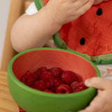 A close of a baby eating raspberries from the Oli & Carol Wally the watermelon wooden bowl  available at Babipur.  