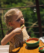 A child eating soup from the Oli & Carol Wally the watermelon wooden bowl and spoon set available at Babipur. 