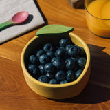 A close up of the Oli & Carol Lou the lemon wooden bowl available at Babipur showing the bowl filled with blueberries