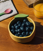 A close up of the Oli & Carol Lou the lemon wooden bowl available at Babipur showing the bowl filled with blueberries
