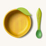 Oli & Carol Lou the lemon wooden bowl and spoon set available at Babipur. Features a decorative green leaf on the bowl.