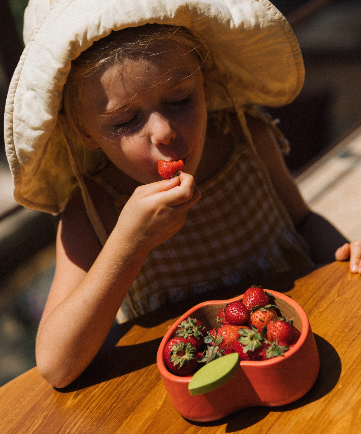 A child eating strawberries from the Oli & Carol Peppa the apple wooden bowl  available at Babipur. 