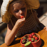 A child eating strawberries from the Oli & Carol Peppa the apple wooden bowl  available at Babipur. 