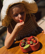 A child eating strawberries from the Oli & Carol Peppa the apple wooden bowl  available at Babipur. 