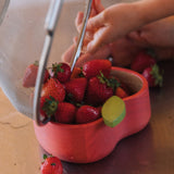 A close up of strawberries being tipped in the Oli & Carol Peppa the apple wooden bowl. Bowl available at Babipur. 