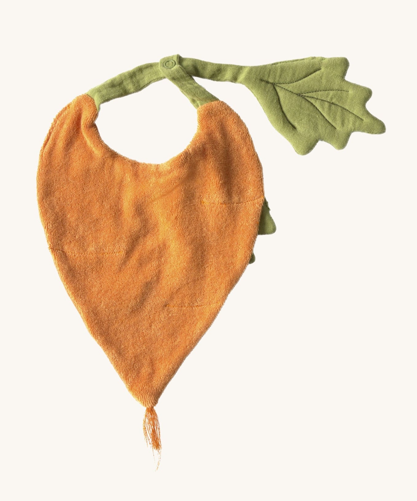 The reverse side of the Oli & Carol Cathy the carrot baby bib available at Babipur. A organic cotton bib in a shape of a orange carrot. Features a popper fastener for size adjustment. 