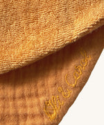 A close up of the  Oli & Carol Peppa the Cathy the carrot baby bib available at Babipur showing the brand name stitch detail on the inside of the bib