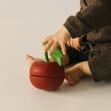 A child playing with the  Oli & Carol cherry stacking toy rattle ball available at Babipur. 