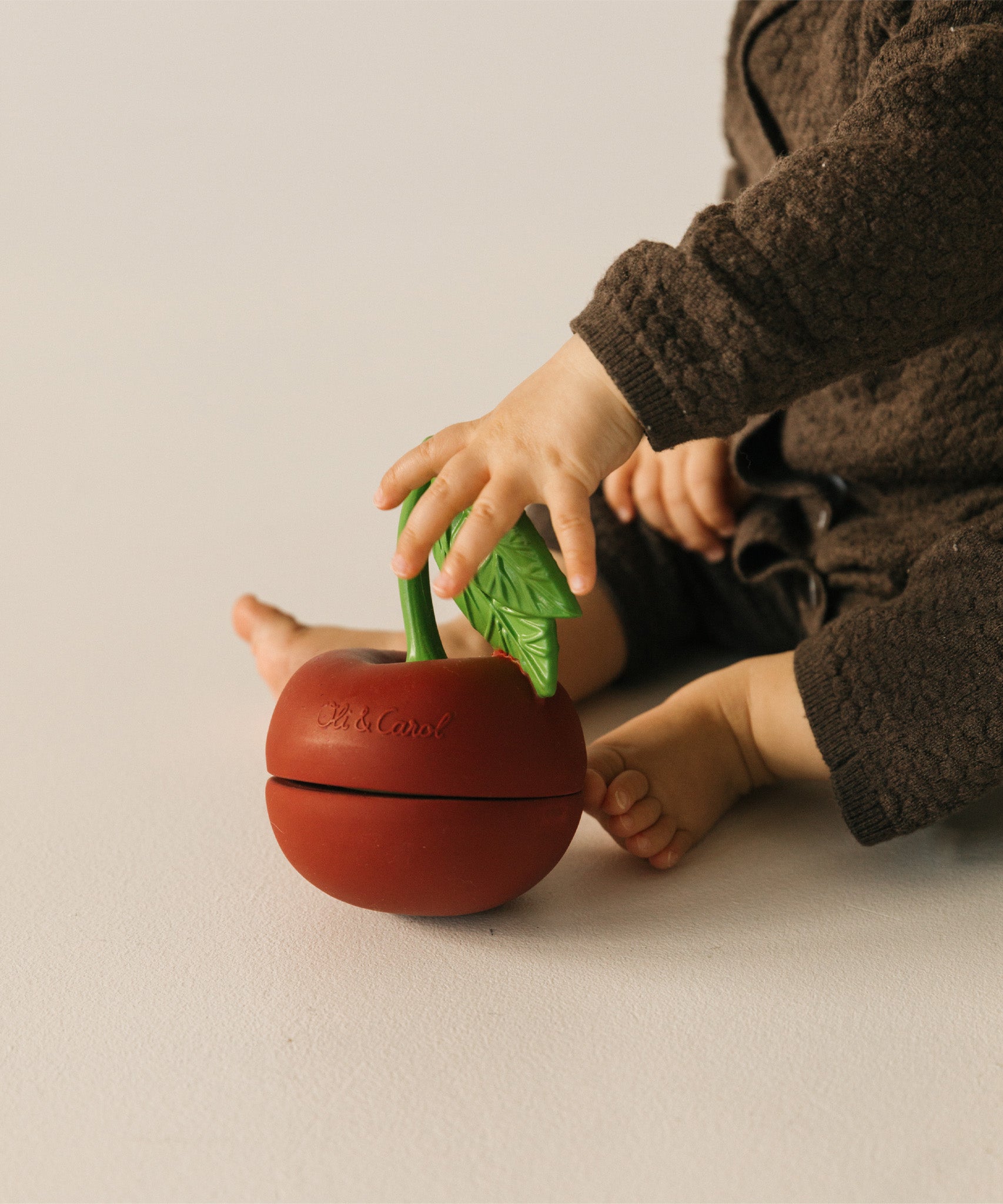 A child playing with the  Oli & Carol cherry stacking toy rattle ball available at Babipur. 