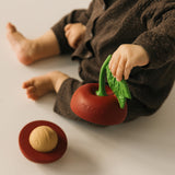 A baby holding one half of the Oli & Carol cherry stacking toy rattle ball available at Babipur.