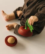 A baby holding one half of the Oli & Carol cherry stacking toy rattle ball available at Babipur.