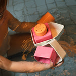 A child holding parts of the Oli & Carol Boat Bath Toy - Orange, in a bath